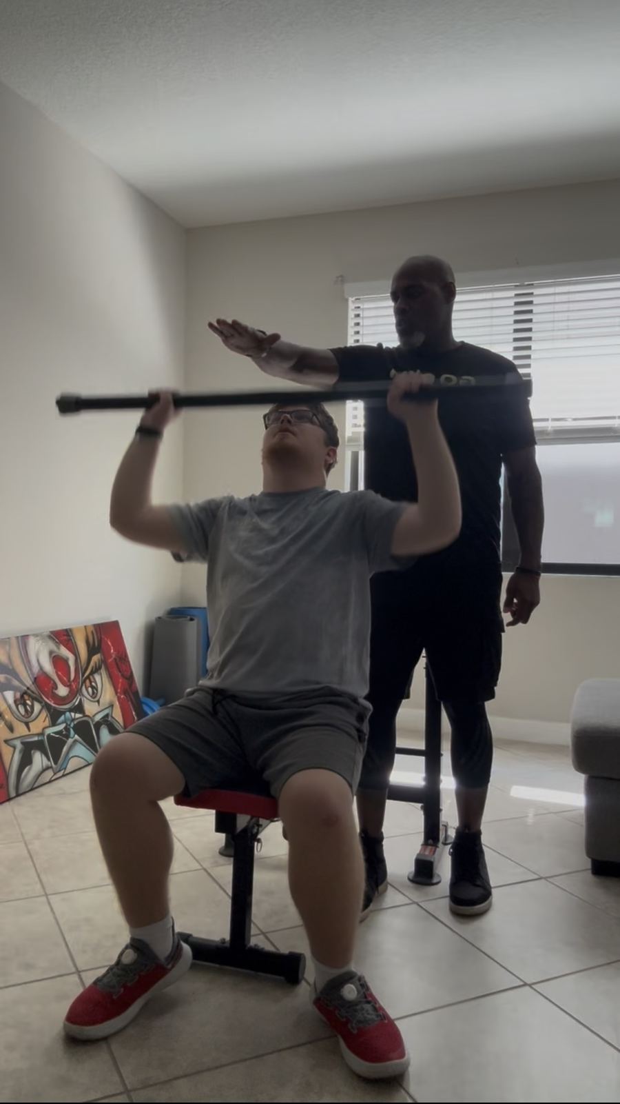 Coach Jerry guiding a seated strength exercise with a client at home