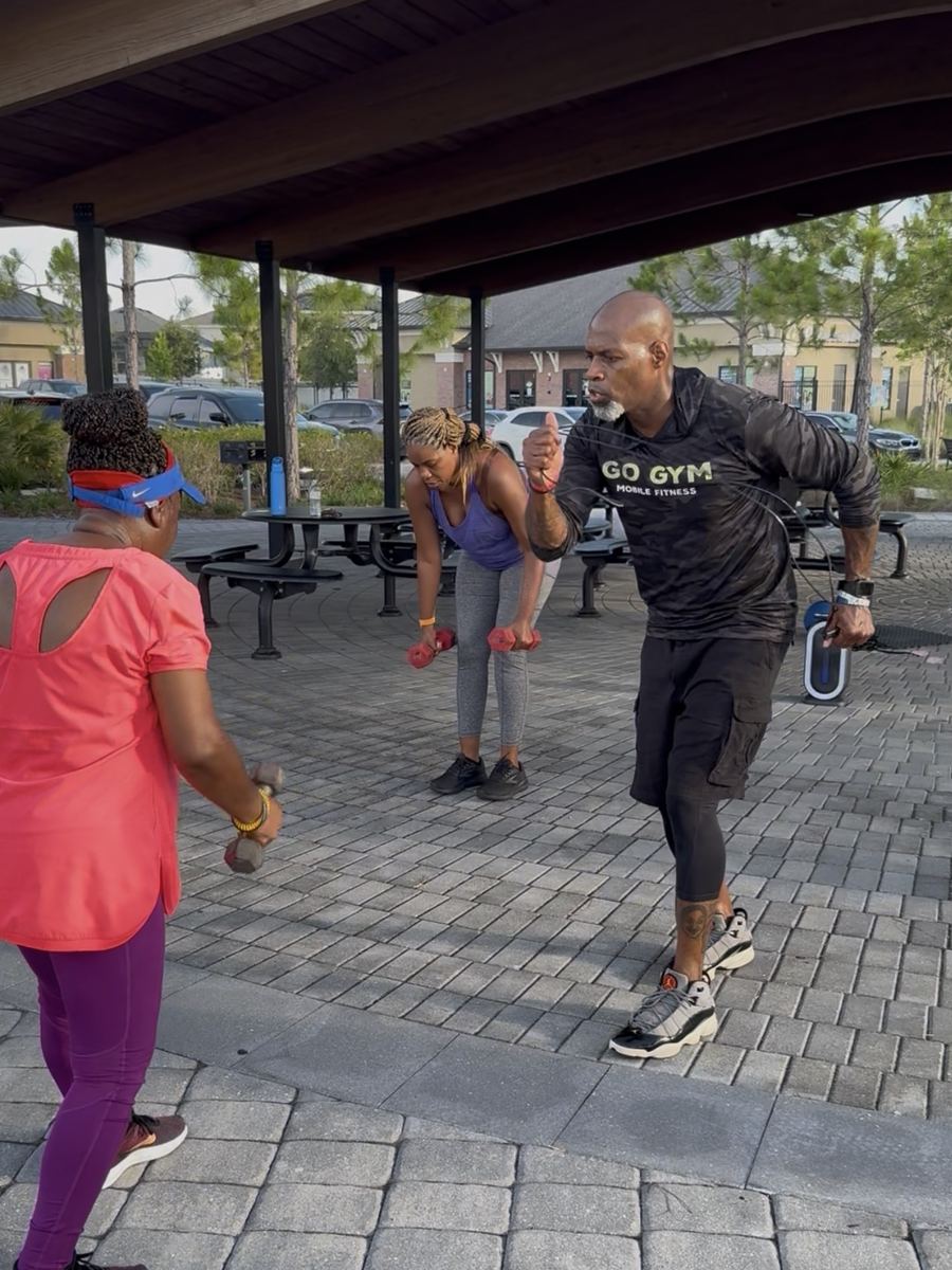Coach Jerry leading a client workout outdoors with weights